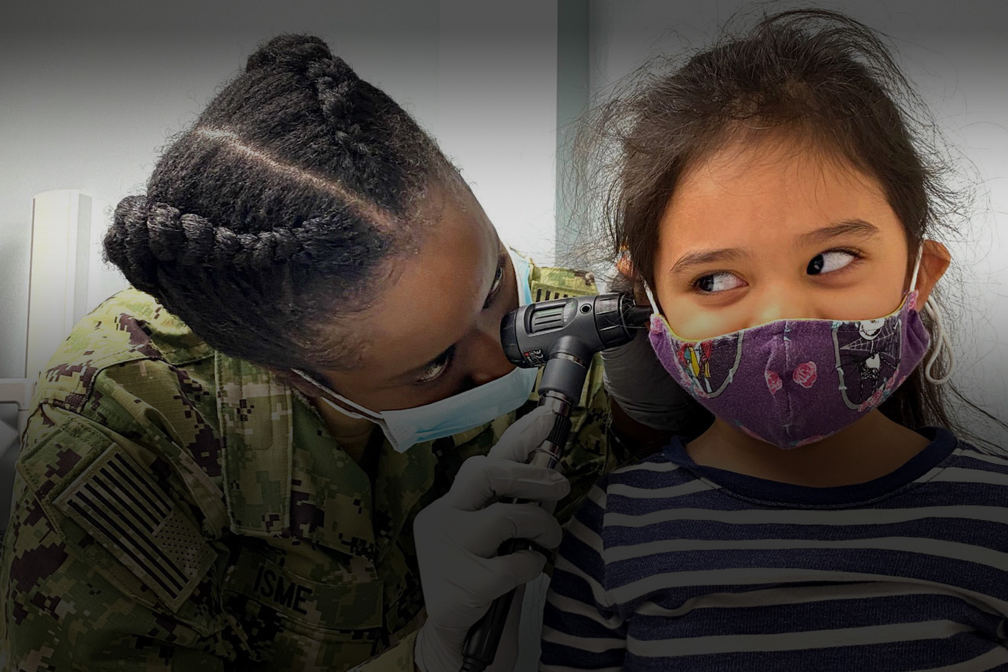Soldier giving ear exam to a child